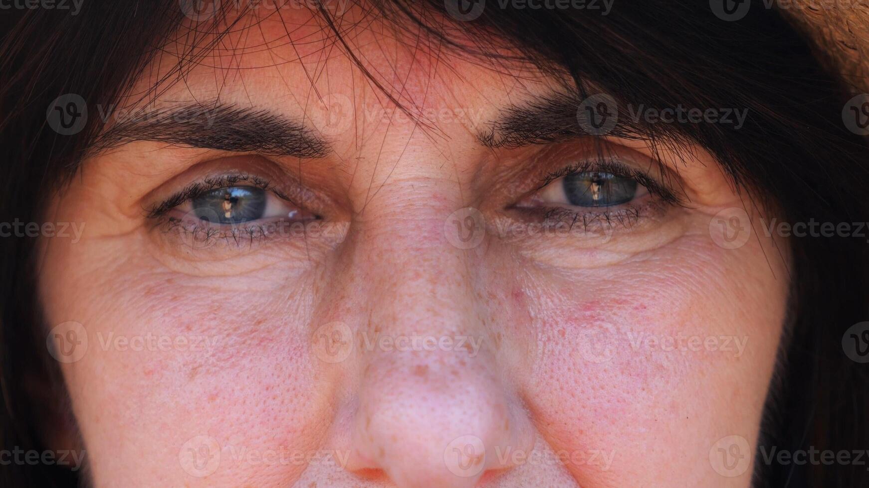 Close up to upset female face looking into camera with a disappointing sight. Upset facial expression of woman with black hair. Unhappy gaze of despairing adult lady. Slow mo photo