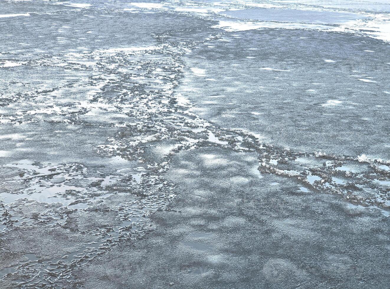 Broken ice of dark blue color on the river. Chunks of crushed ice on dark water. Abstract ice background. Blue background with cracks on the ice surface. Cracks of frozen water photo