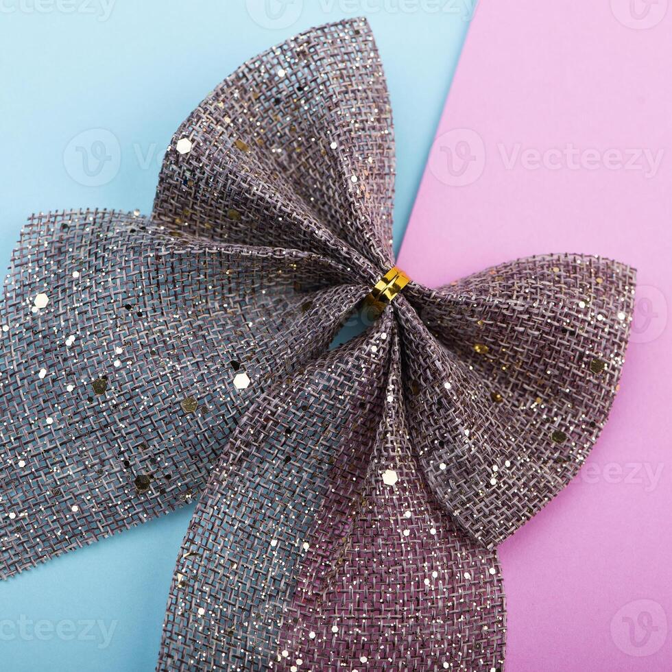 Burlap bow with gold glitter on pink and blue background, Christmas holiday decor photo