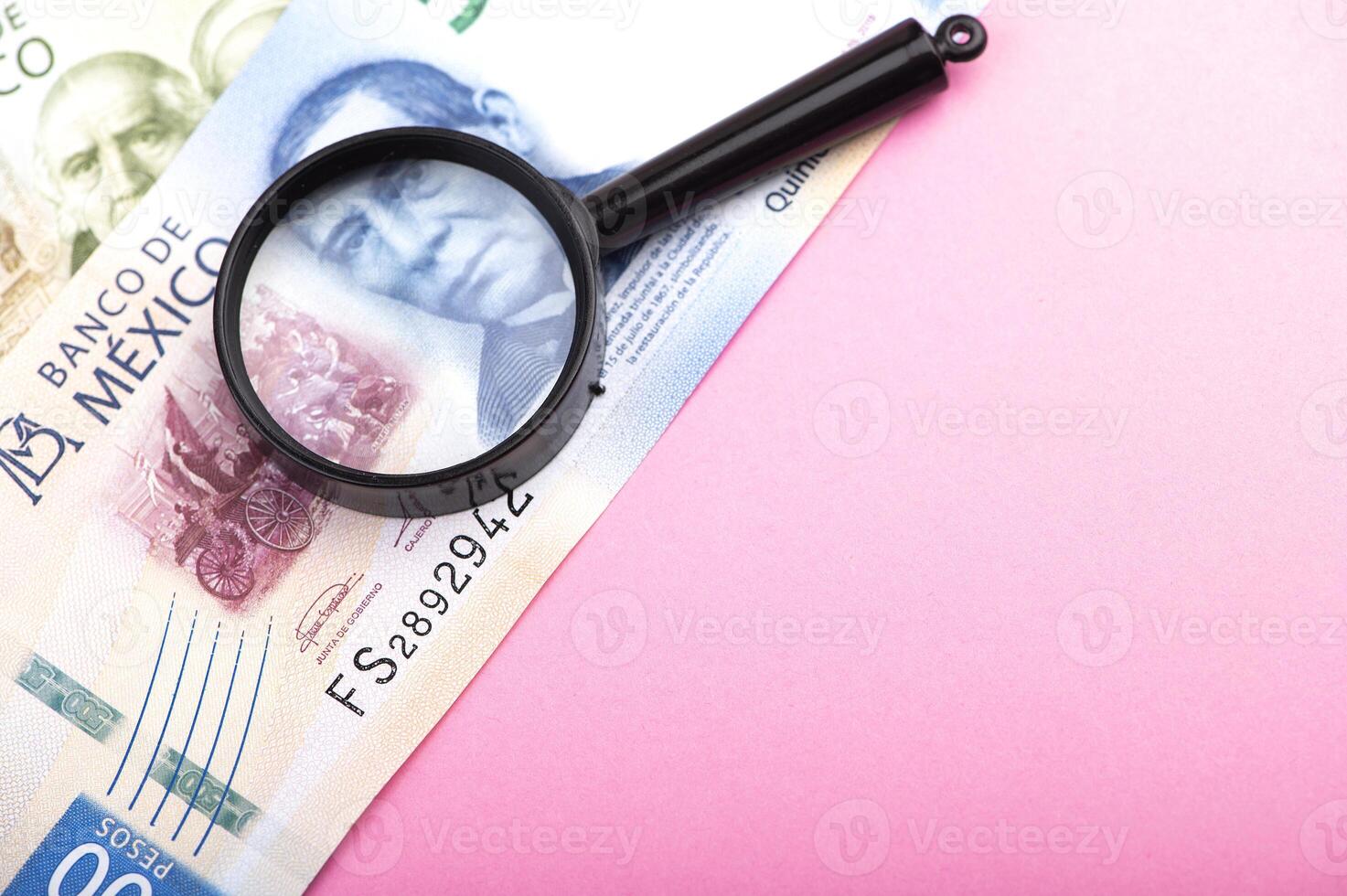 Paper currency of Mexico and magnifier on pink background, mexican pesos photo