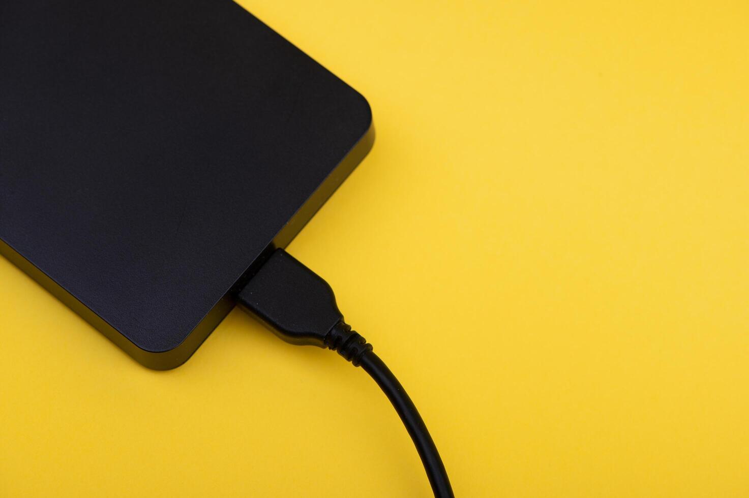 Black external portable hard disk drives isolated on yellow background photo