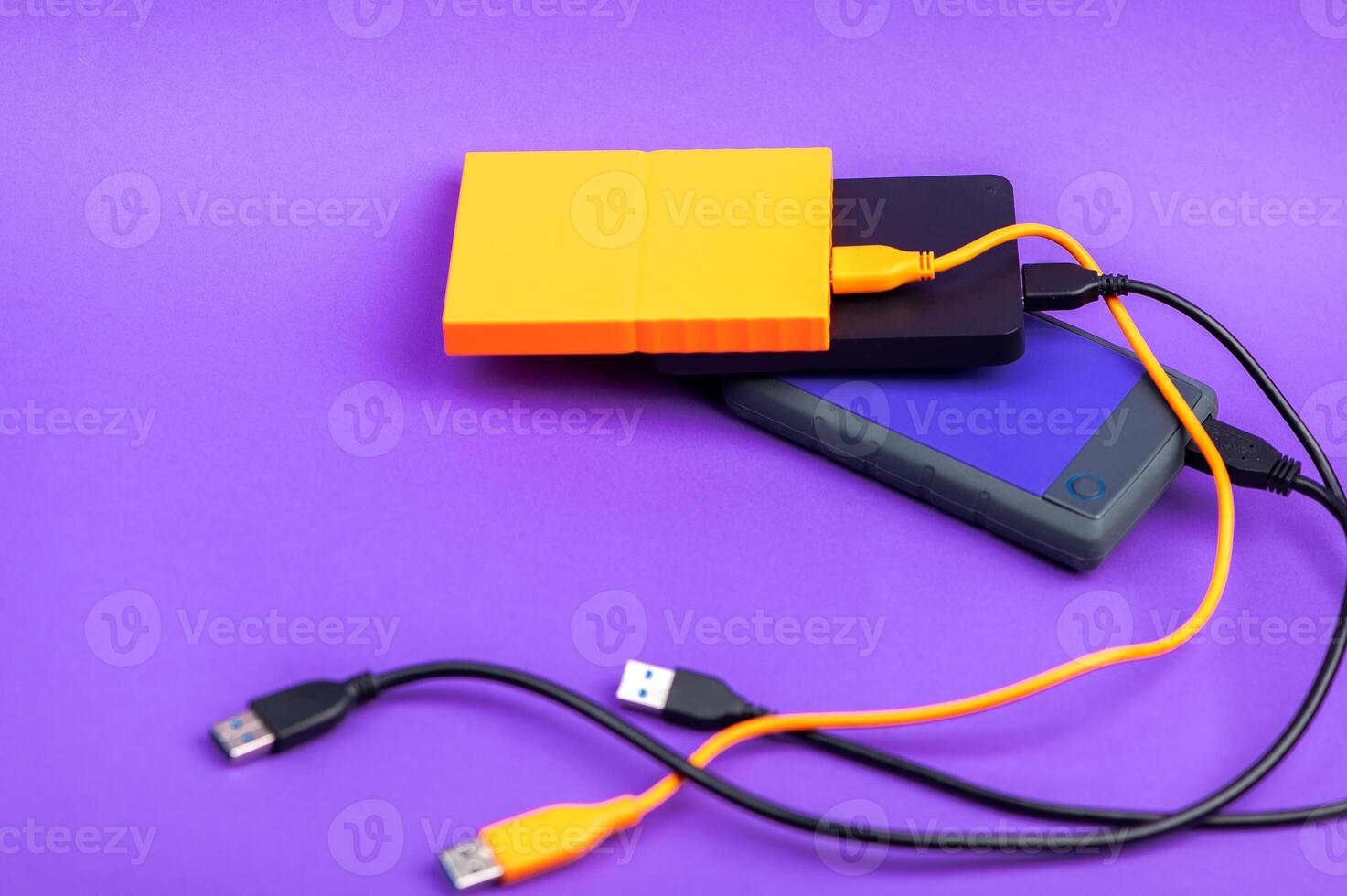 Multicolored external portable hard disk drives isolated on violet background photo