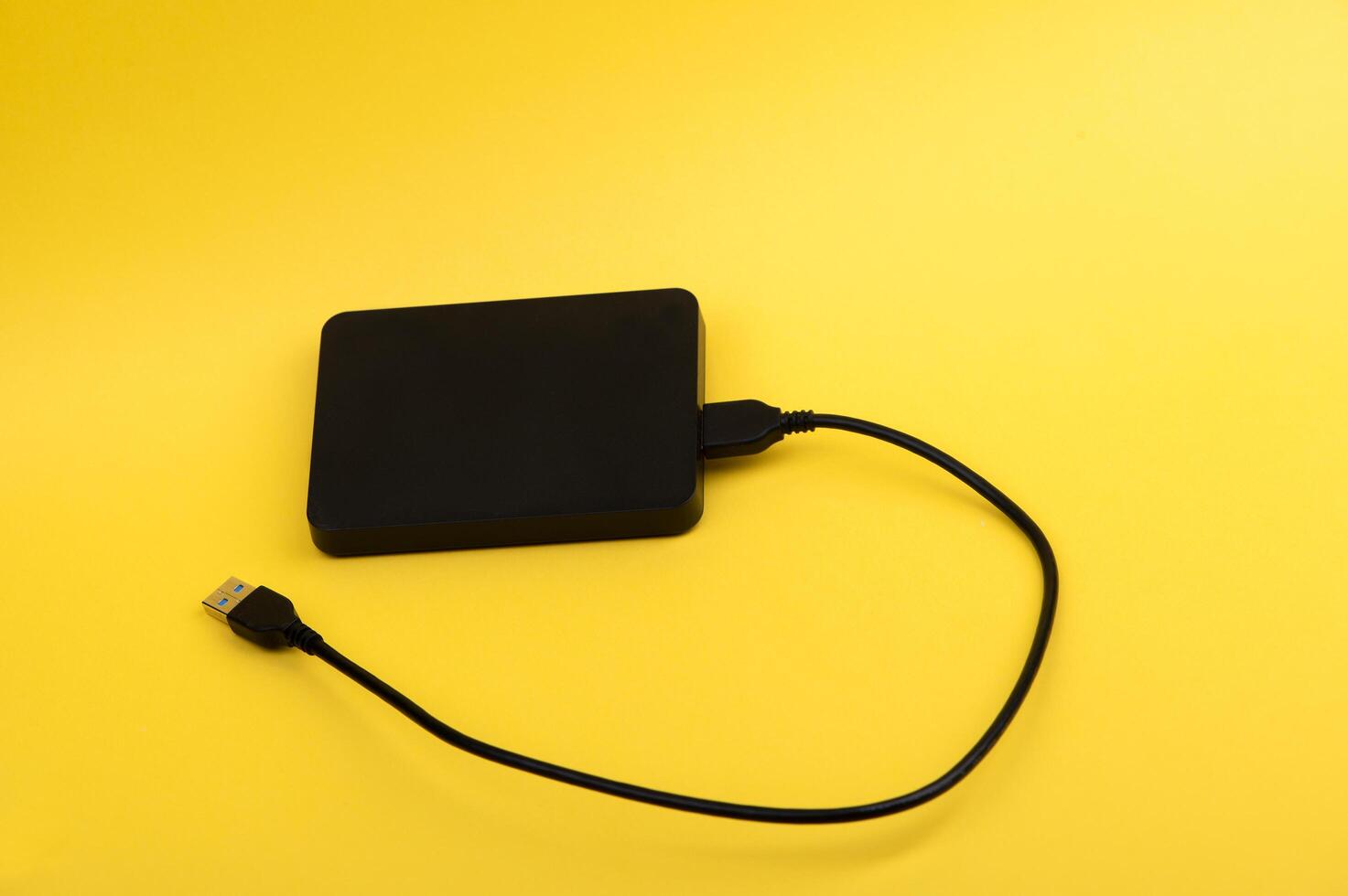 Black external portable hard disk drives isolated on yellow background photo