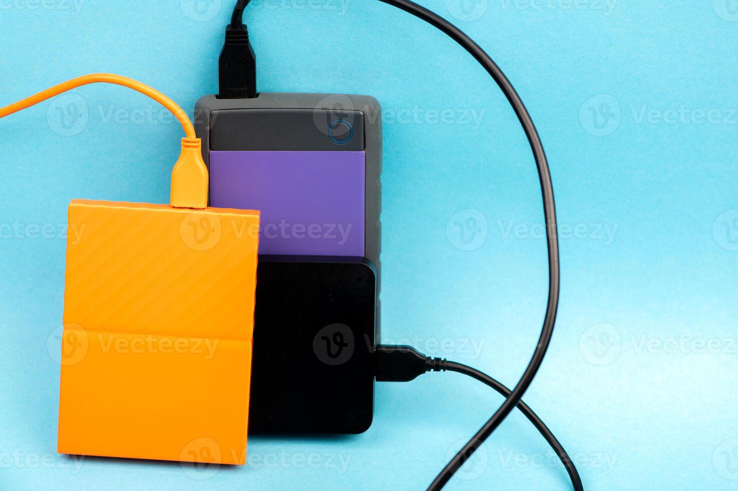 Two external portable hard disk drives isolated on light blue background photo