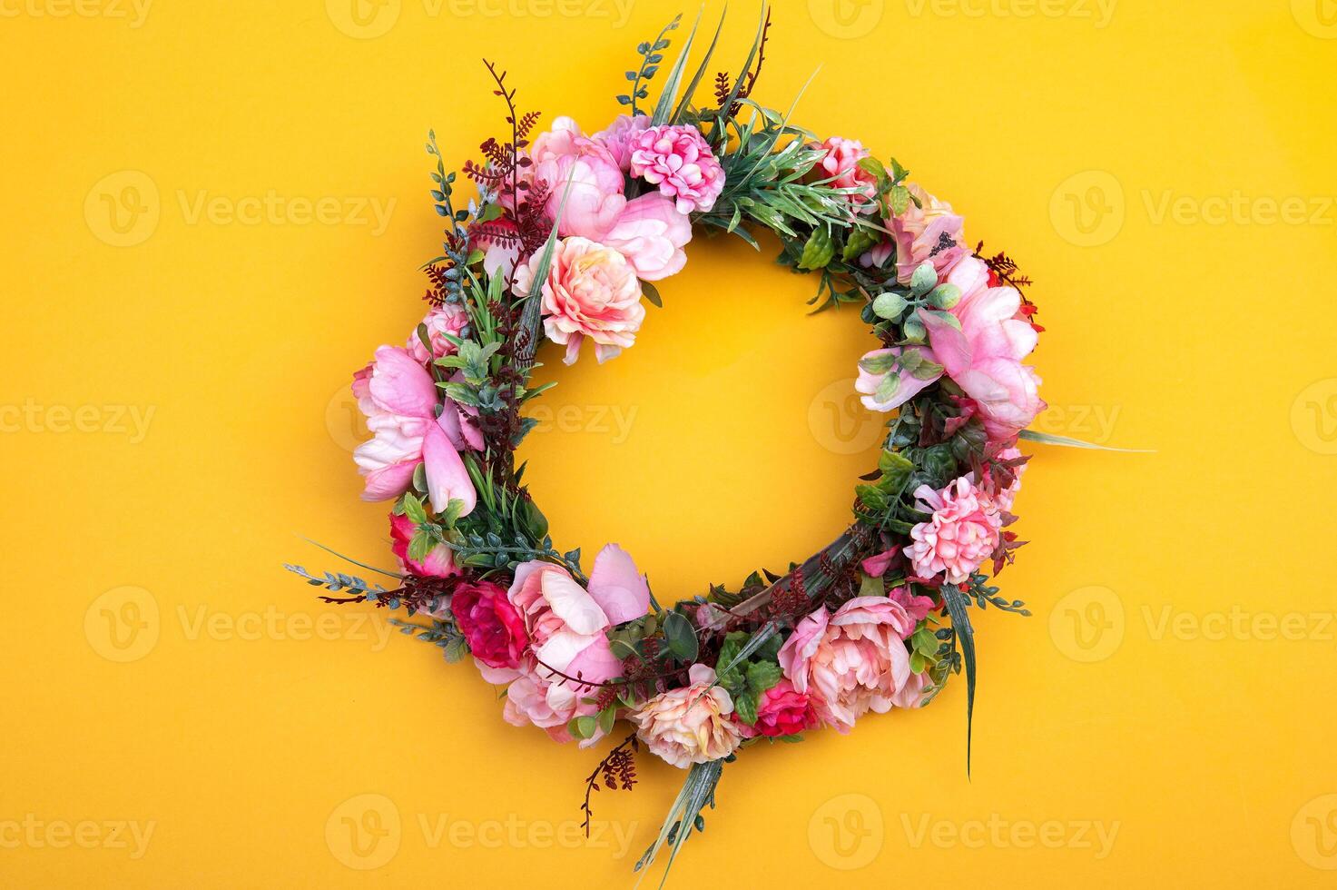 Colorful artificial flowers wreath isolated on yellow photo