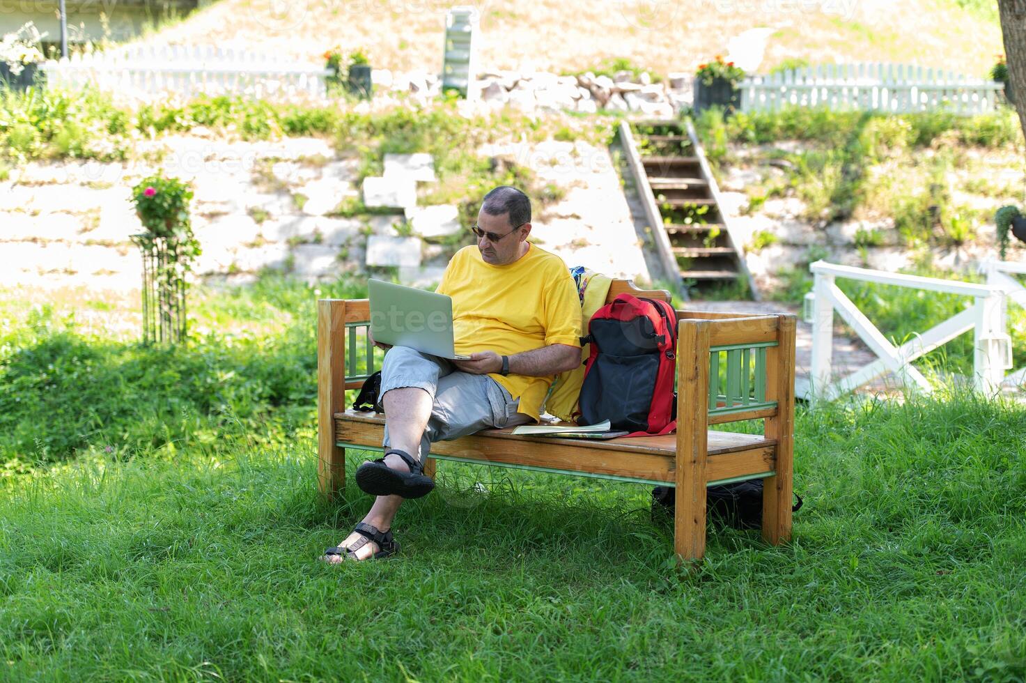 A man working and typing on laptop keyboard while sitting in the park, hand on laptop photo