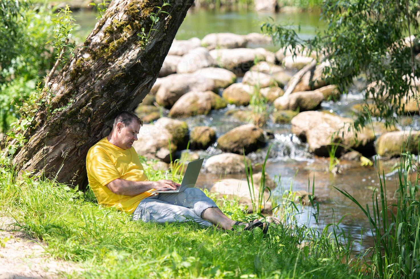 A man working and typing on laptop keyboard while sitting in the park, hand on laptop photo