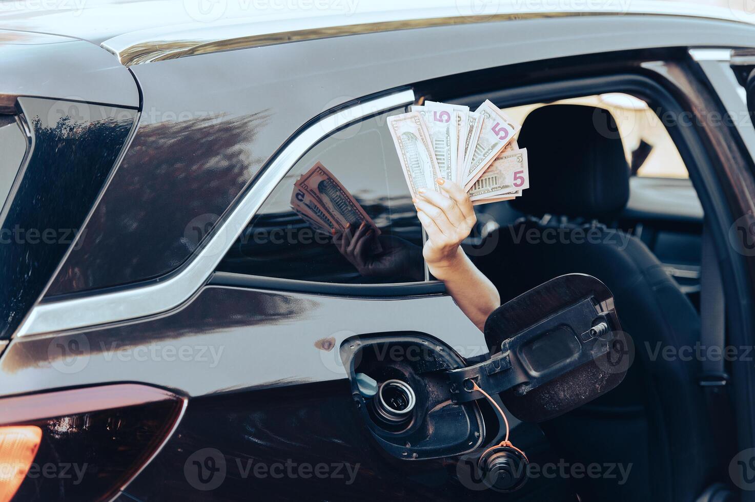 Desperate woman hold cash dollar bills next to car with an open tank, concept of rising fuel prices photo