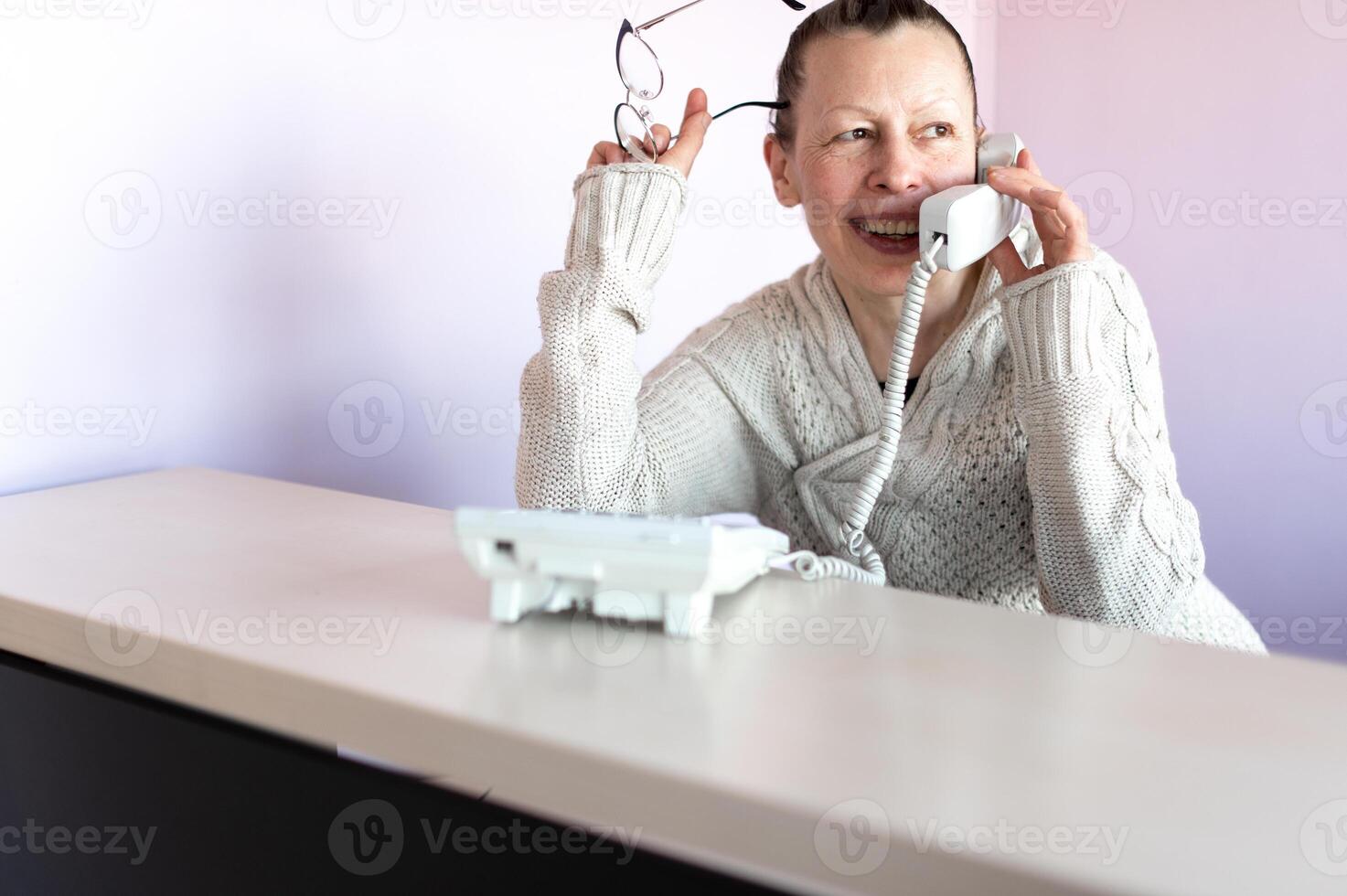middle aged business woman talking on the phone at her office workplace photo