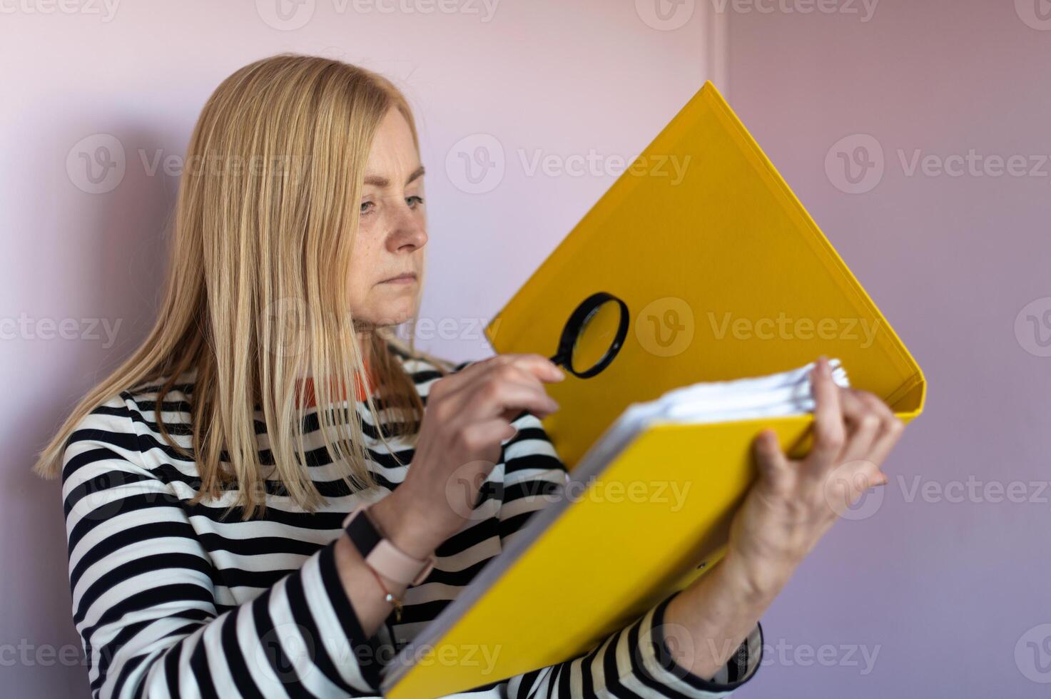 Middle aged funny woman with magnifying glass reading document on gray wall background isolated photo