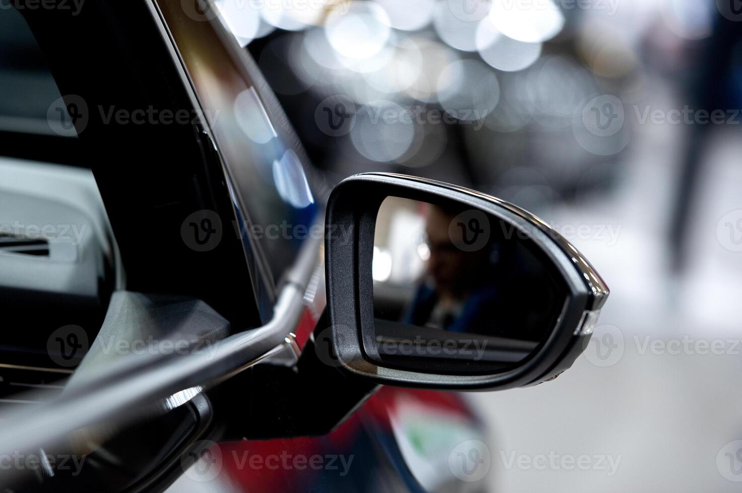 A blurred night scene viewed from a car side mirror capturing the motion of city lights and passing vehicles on a wet road photo