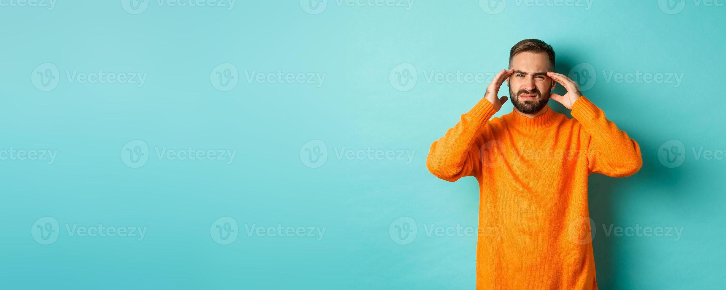 Photo of caucasian man touching head, feeling sick, have headache or migraine, hangover after party, standing over light blue background