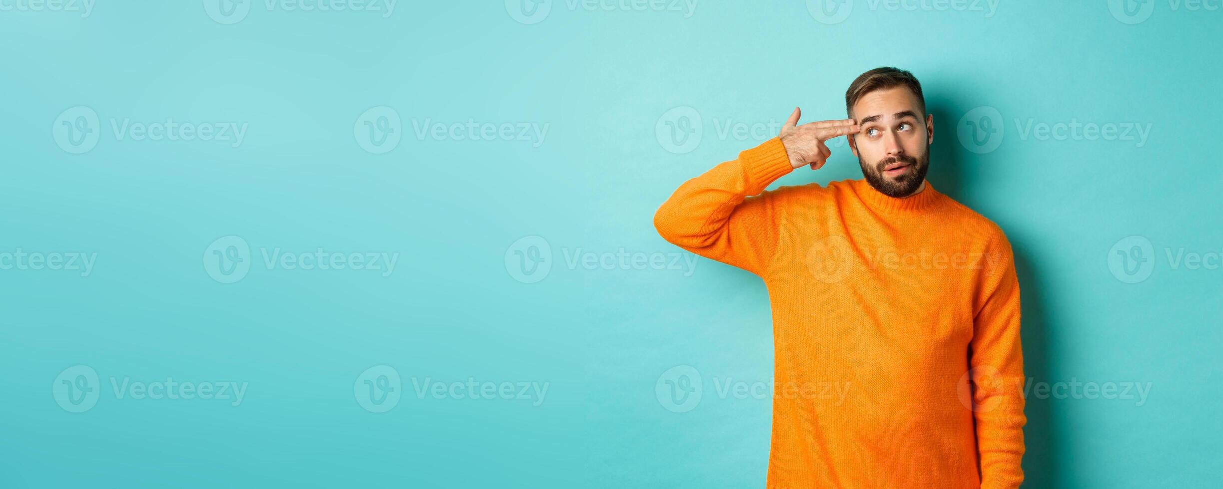 Man shooting himself in head, make finger gun near temple and roll eyes annoyed, standing bothered against light blue background photo