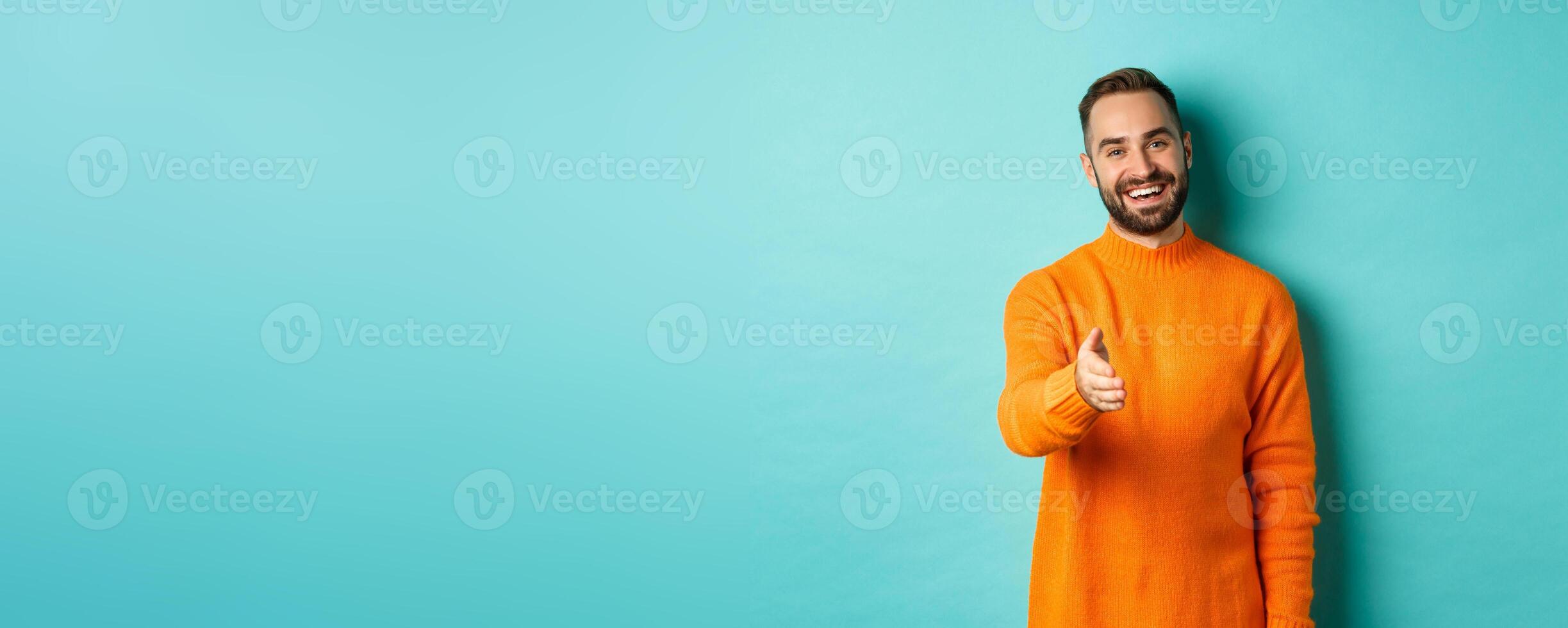 Friendly nice guy extend hand for handshake, greeting you and smiling, saying hello, standing over light blue background photo