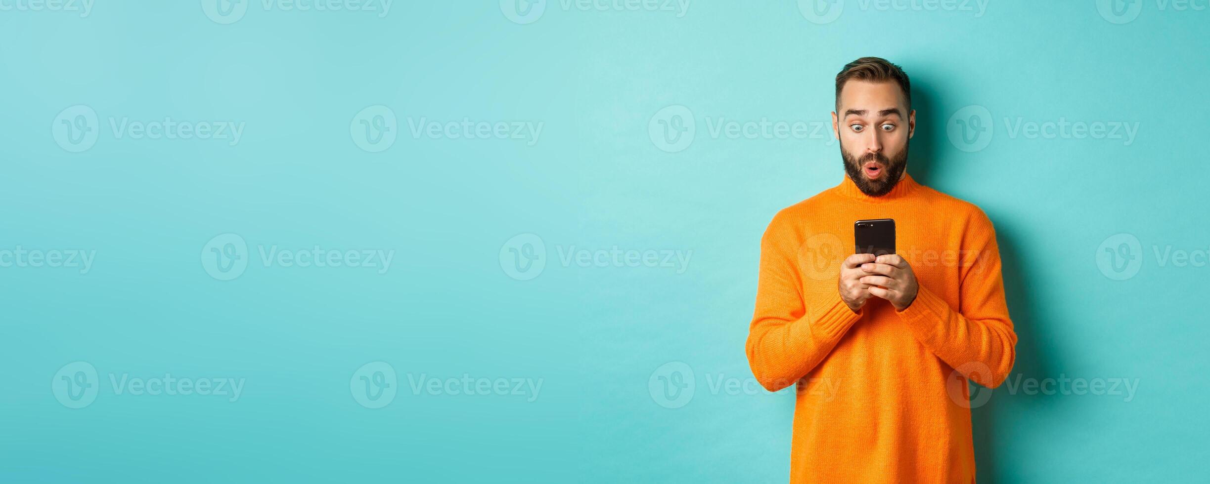 Image of man reading message with surprised face, standing amazed over light blue background photo