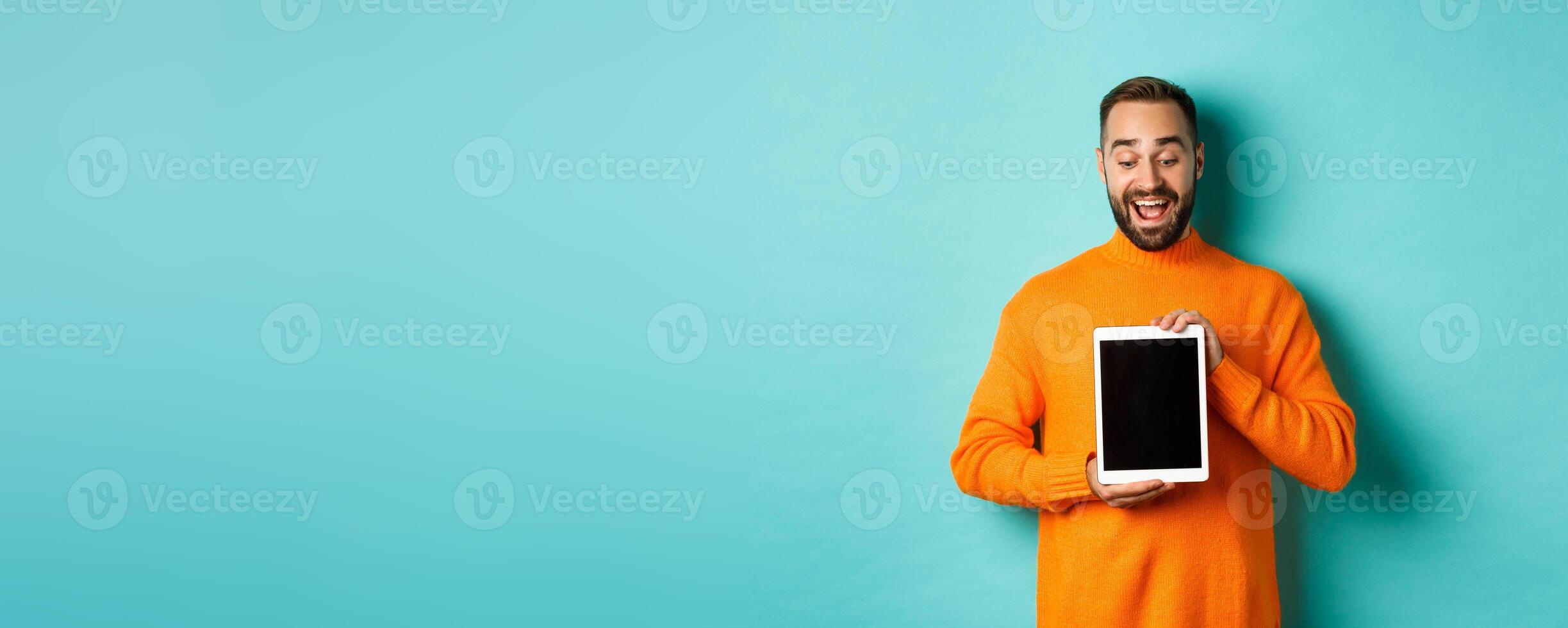 Technology. Cheerful adult man looking and showing digital tablet screen, standing over light blue background photo