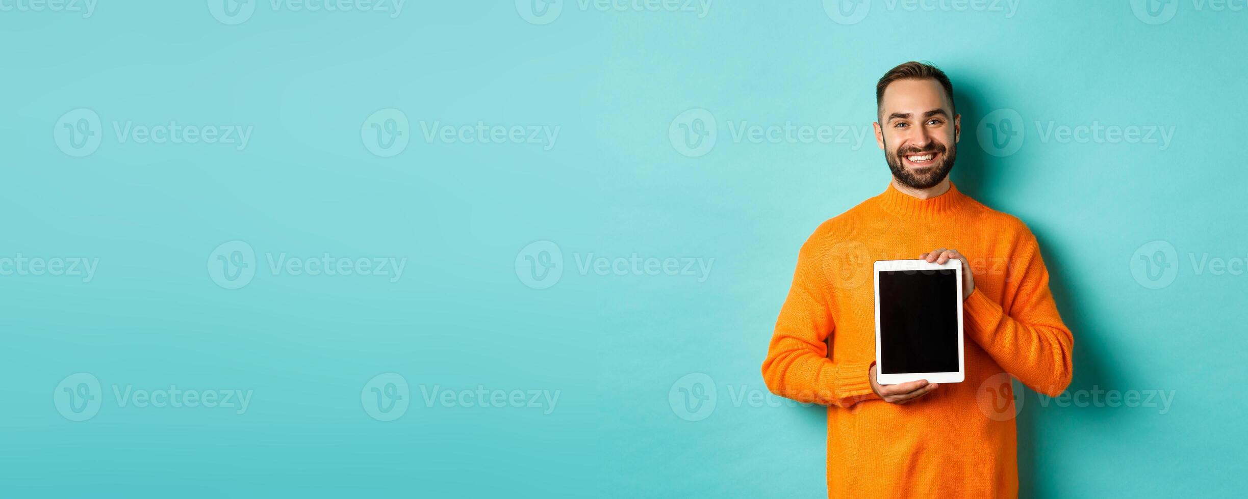 Technology. Smiling handsome man showing digital tablet screen, demonstrating application, standing over turquoise background photo