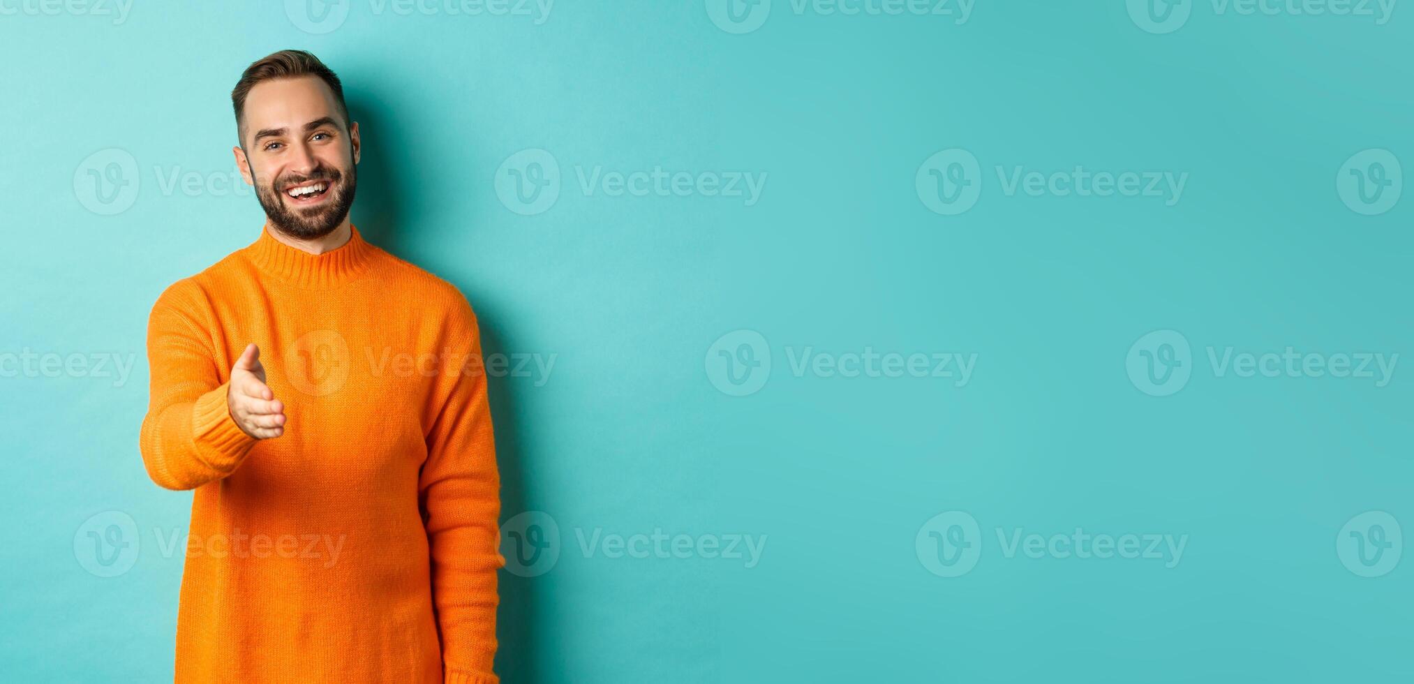 Friendly nice guy extend hand for handshake, greeting you and smiling, saying hello, standing over light blue background photo