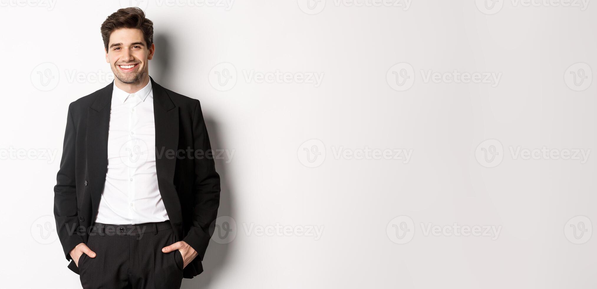 Image of handsome caucasian man in party suit, smiling pleased, attend formal event, standing over white background photo