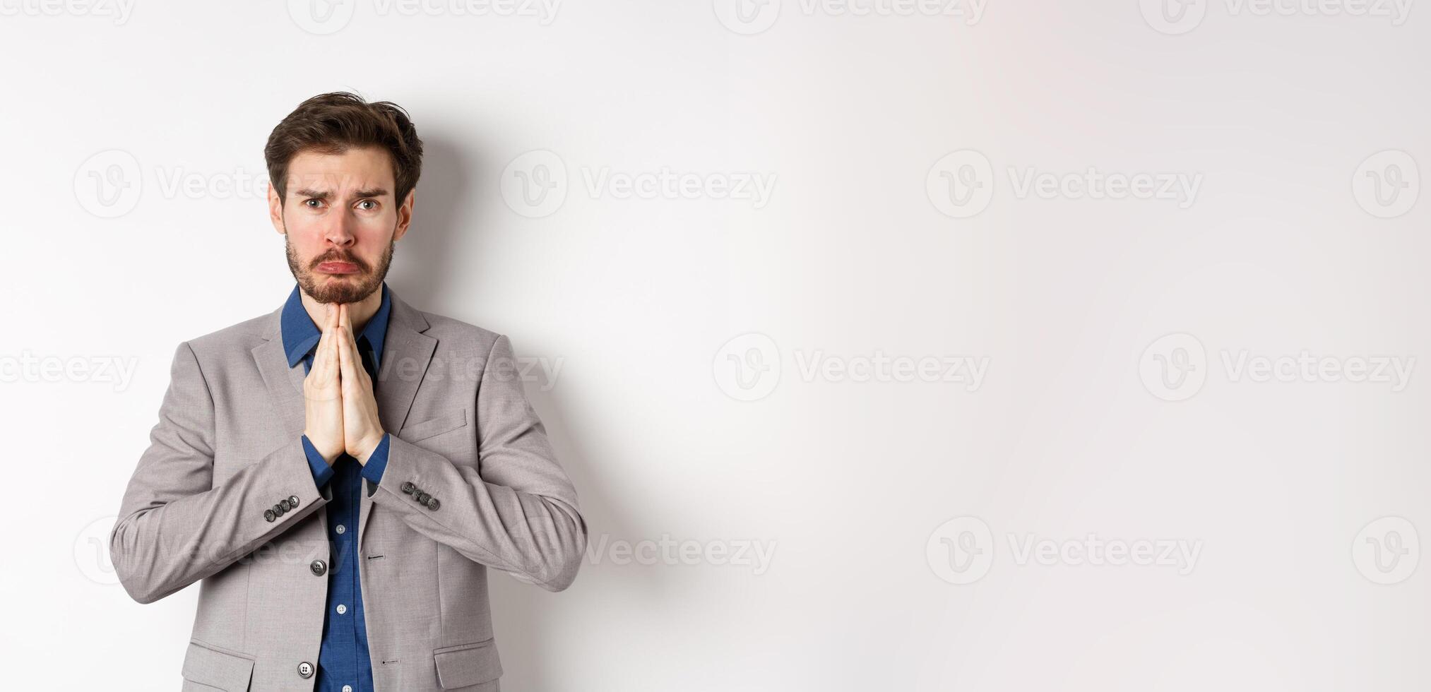 Miserable whining businessman asking for loan, need help and begging you, sobbing and say please with sad face, standing on white background, ask for forgiveness photo