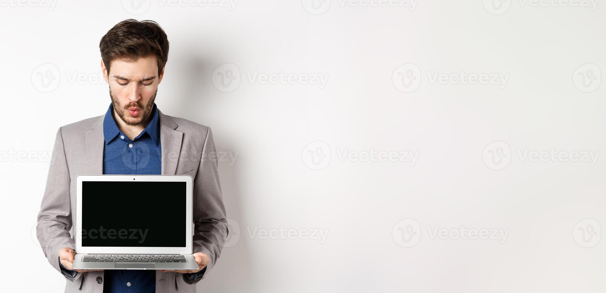 Handsome caucasian businessman in suit showing empty laptop screen, demonstrate promo, standing on white background photo