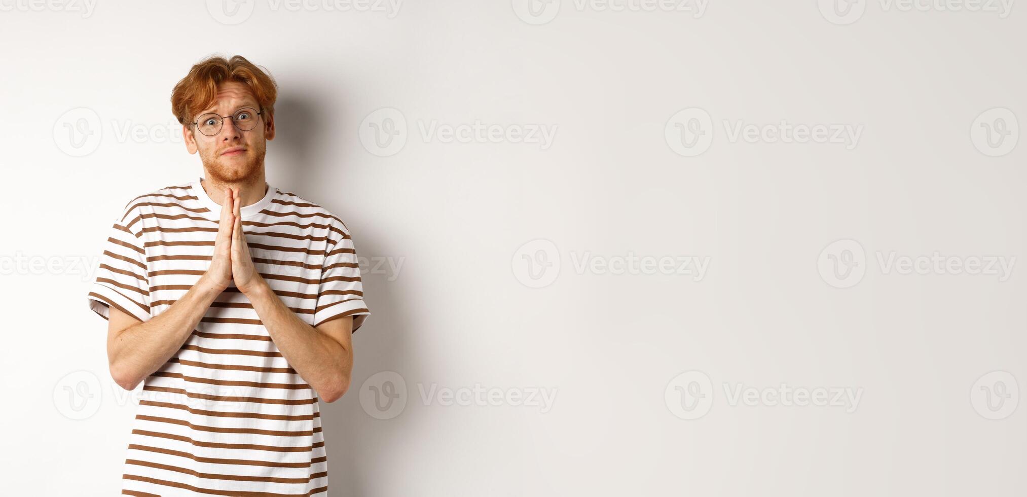 Cute redhead man in glasses asking for help, pleading and looking clingy at camera, begging for favour, white background photo