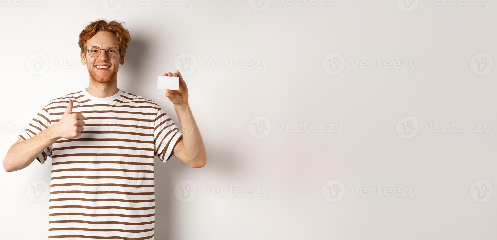 Shopping and finance concept. Satisfied male bank client showing thumbs-up and plastic credit card, smiling happy at camera photo