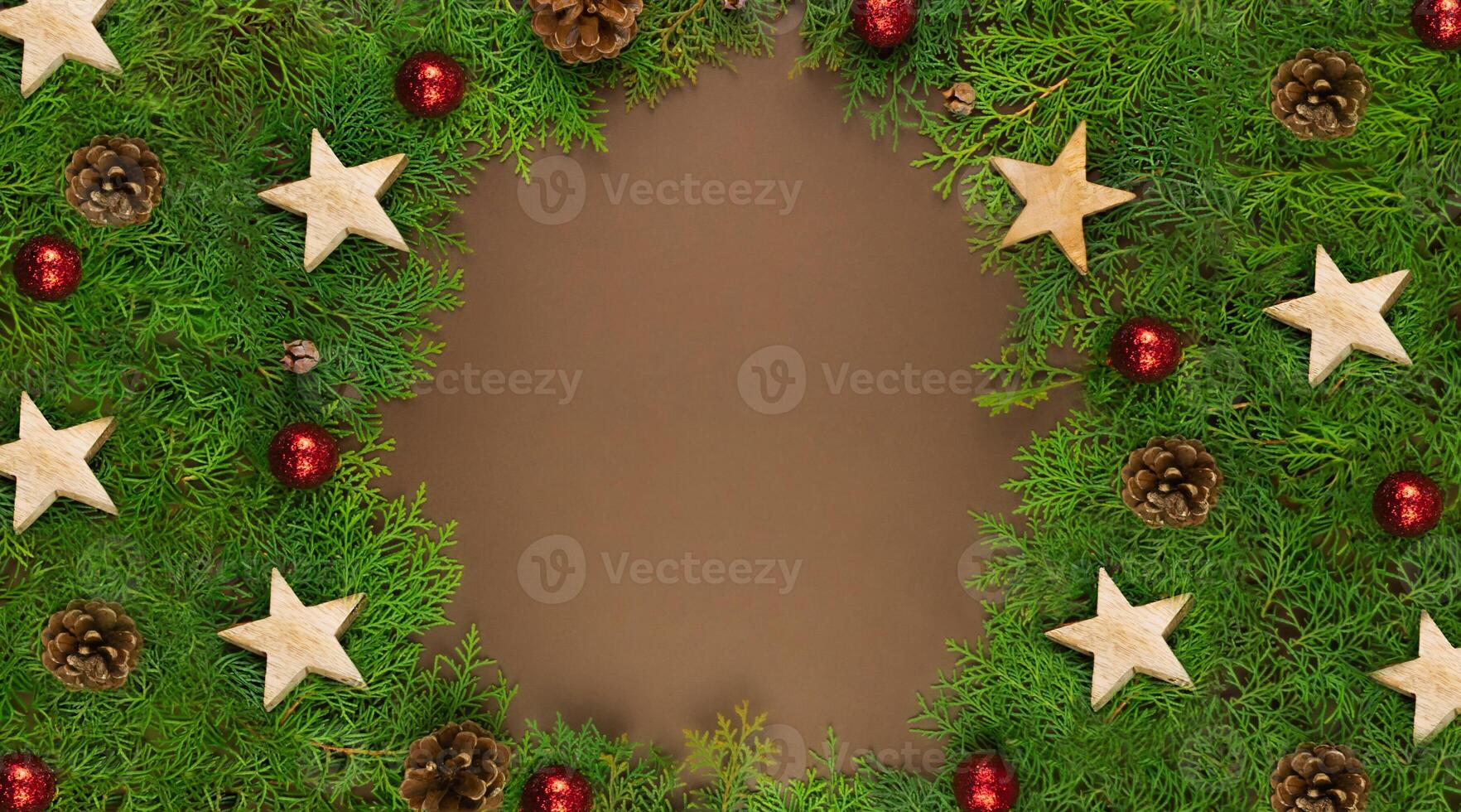 Christmas card on brown background with Thuja branches, red balls, wooden stars and place for text. photo