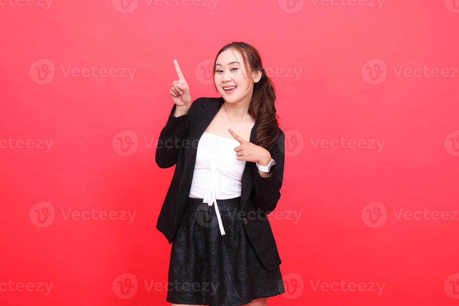 gesture of cheerful young Asian office female wearing a black formal suit, both hands pointing obliquely to the right, for corporate content, fashion, advertising, broadcasts photo