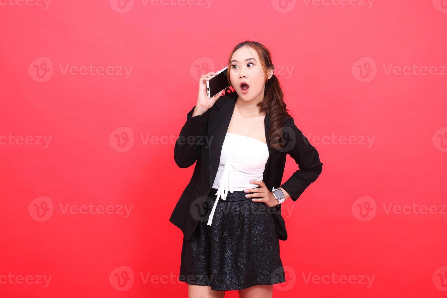 gesture of young asian career woman shocked candid wearing formal black suit while calling someone via smartphone, for technology, business, advertising, financial content photo