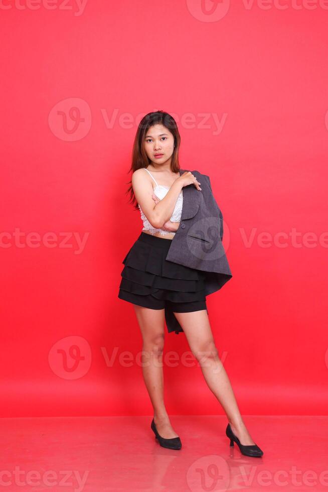 full body Asian girl in sexy elegant gray suit with arms folded in long hair jacket, white skin in studio with red background. for corporate concepts, fashion and advertising photo