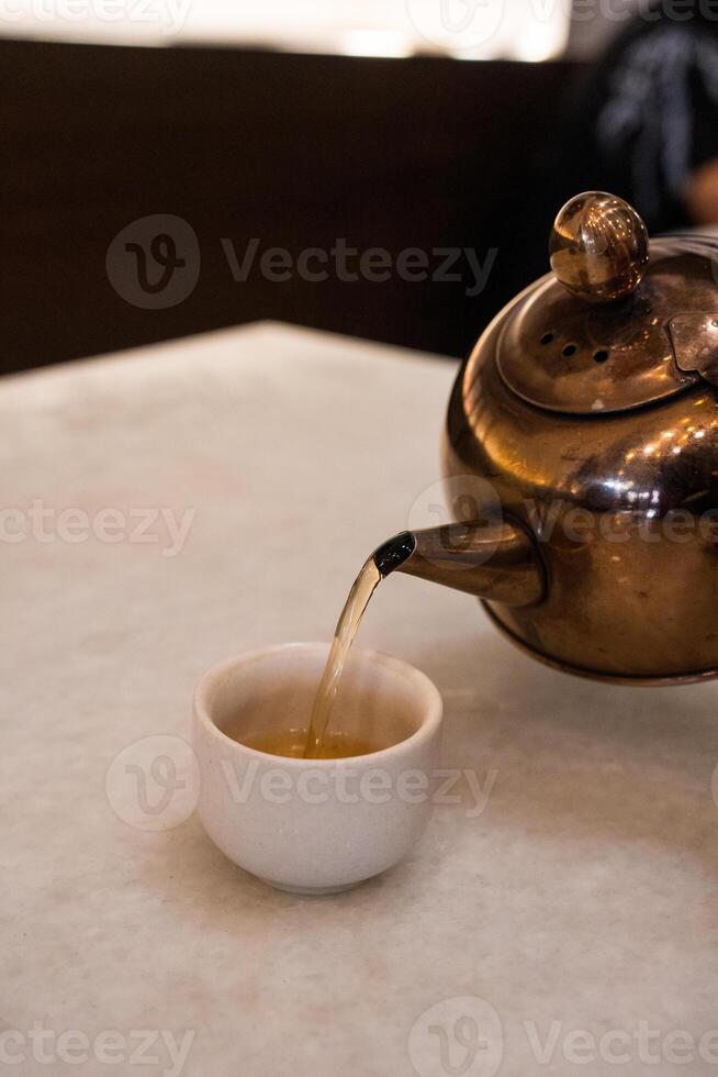 Hand pouring hot tea from teapot photo