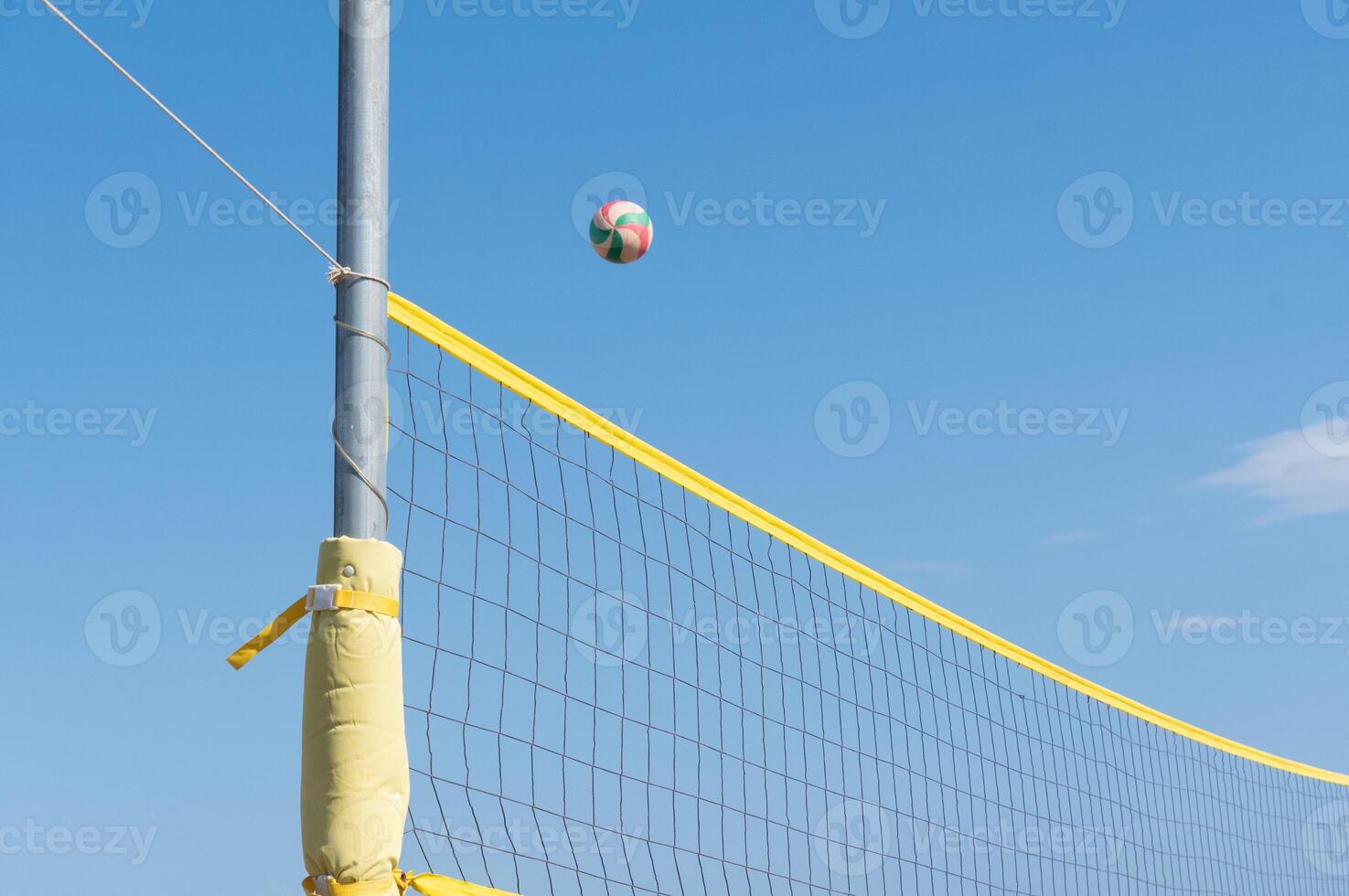 the ball flies through the net against the background of a clear blue sky, beach volleyball in the sea or ocean in summer, ball matches and active activities, copy space photo