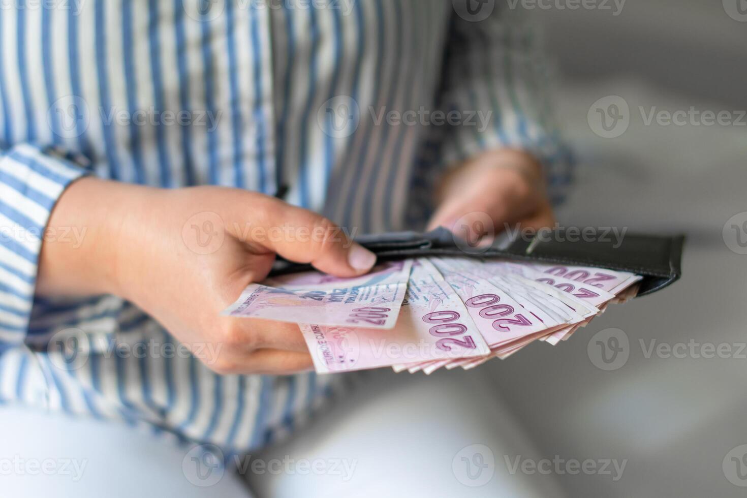 Leather wallet with money in the hands of a woman who takes out a pack of 200 Turkish lira bills from wallet, a lot of money but little value, high inflation in Turkey photo