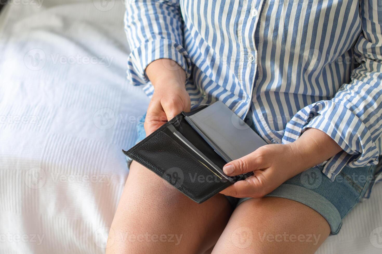 Leather empty wallet in the hands of a woman suffering without money, sitting in the room on the edge of the bed, unemployment concept, economic crisis, photo