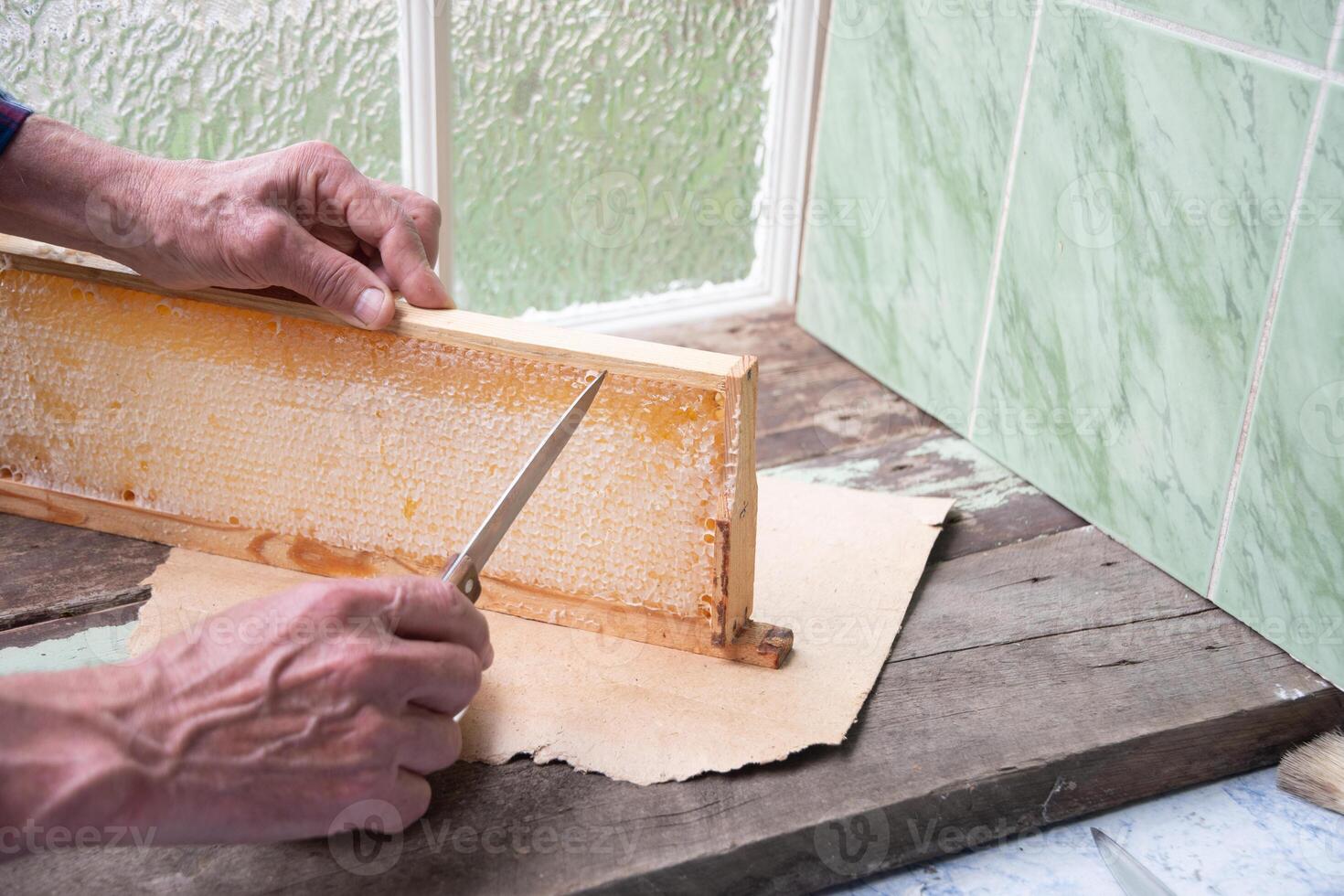 man cuts honeycombs from a honey frame with a knife for eating for tea, honey in honeycombs is good for the health of a pensioner, High quality photo