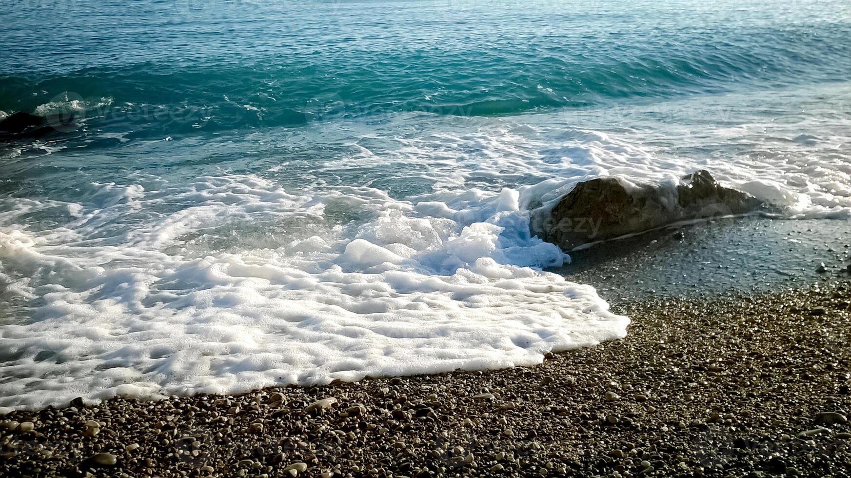 Foamy waves of a sea blue water rocks of the shore in Antibes, France photo