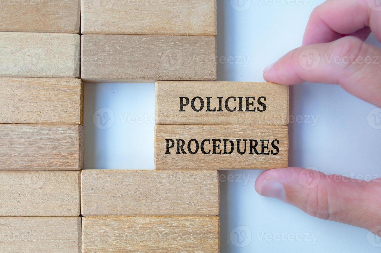 Top view of hand pulling out wooden blocks with text, policies and procedures photo