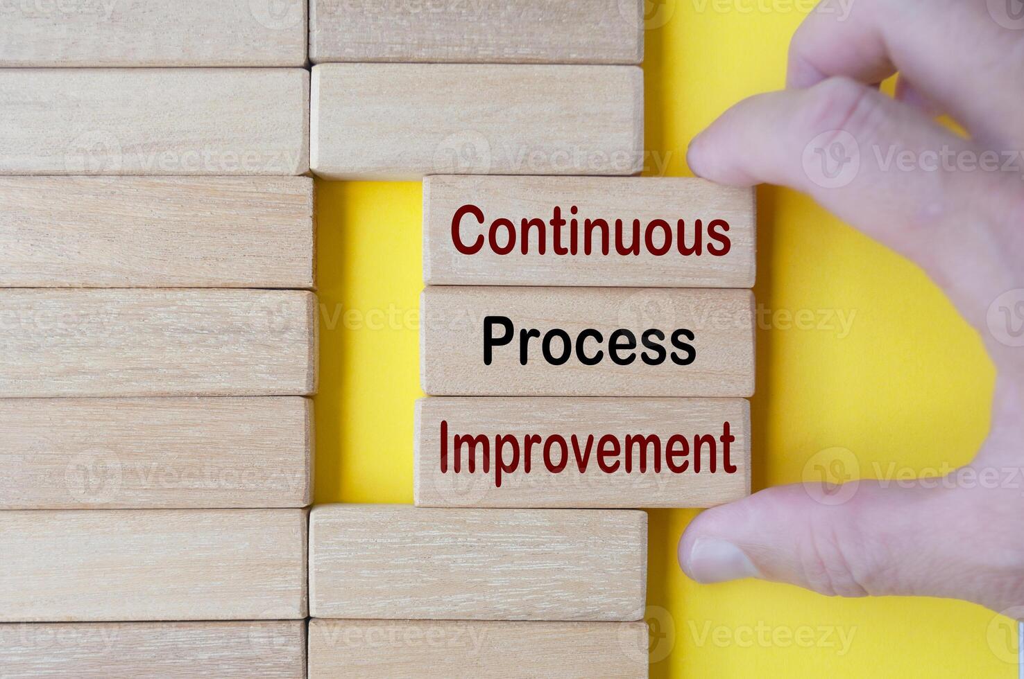 Hand pulling wooden blocks with continuous process improvement text. Business culture and Operational excellence concept photo