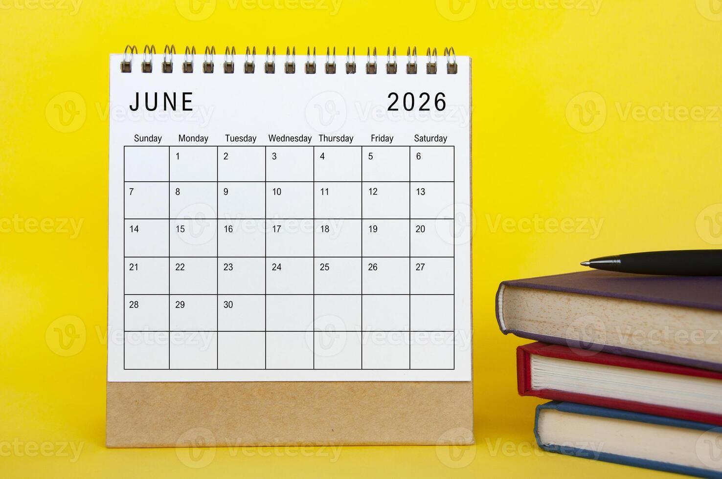 June 2026 calendar with yellow cover background and books. New month and calendar concept photo
