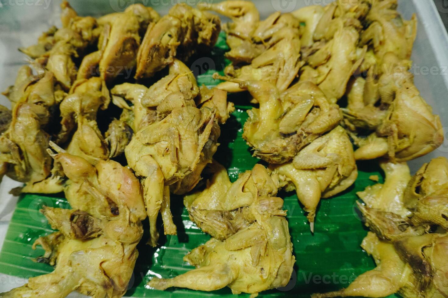 Marinated pigeon or dove meat prepared on top of banana leaf, ready to be cooked. photo