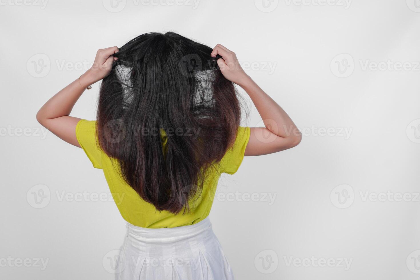 Back portrait of an Asian woman wearing a yellow t-shirt feeling stressed and having headache isolated by white background. photo