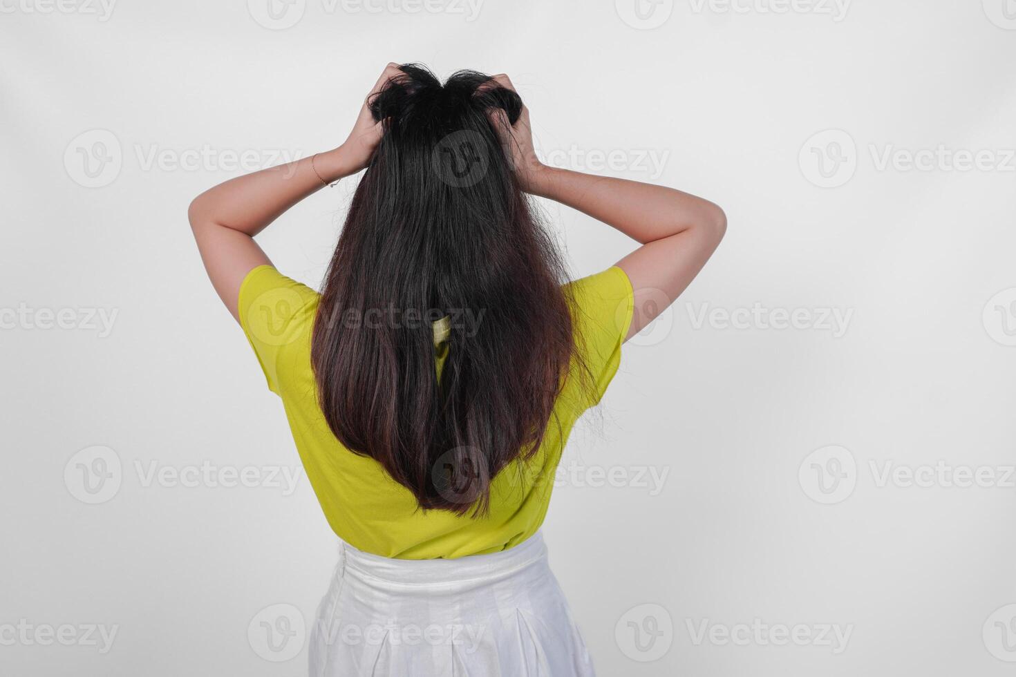 Back portrait of an Asian woman wearing a yellow t-shirt feeling stressed and having headache isolated by white background. photo