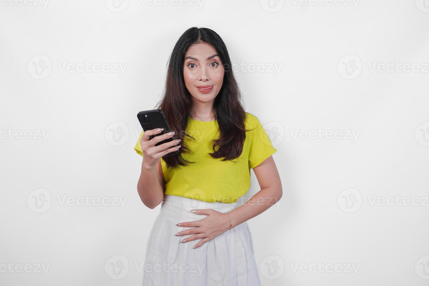 Hungry Asian woman is holding a cell phone and looking to the copy space upwards, thinking what to eat, isolated by white background. photo