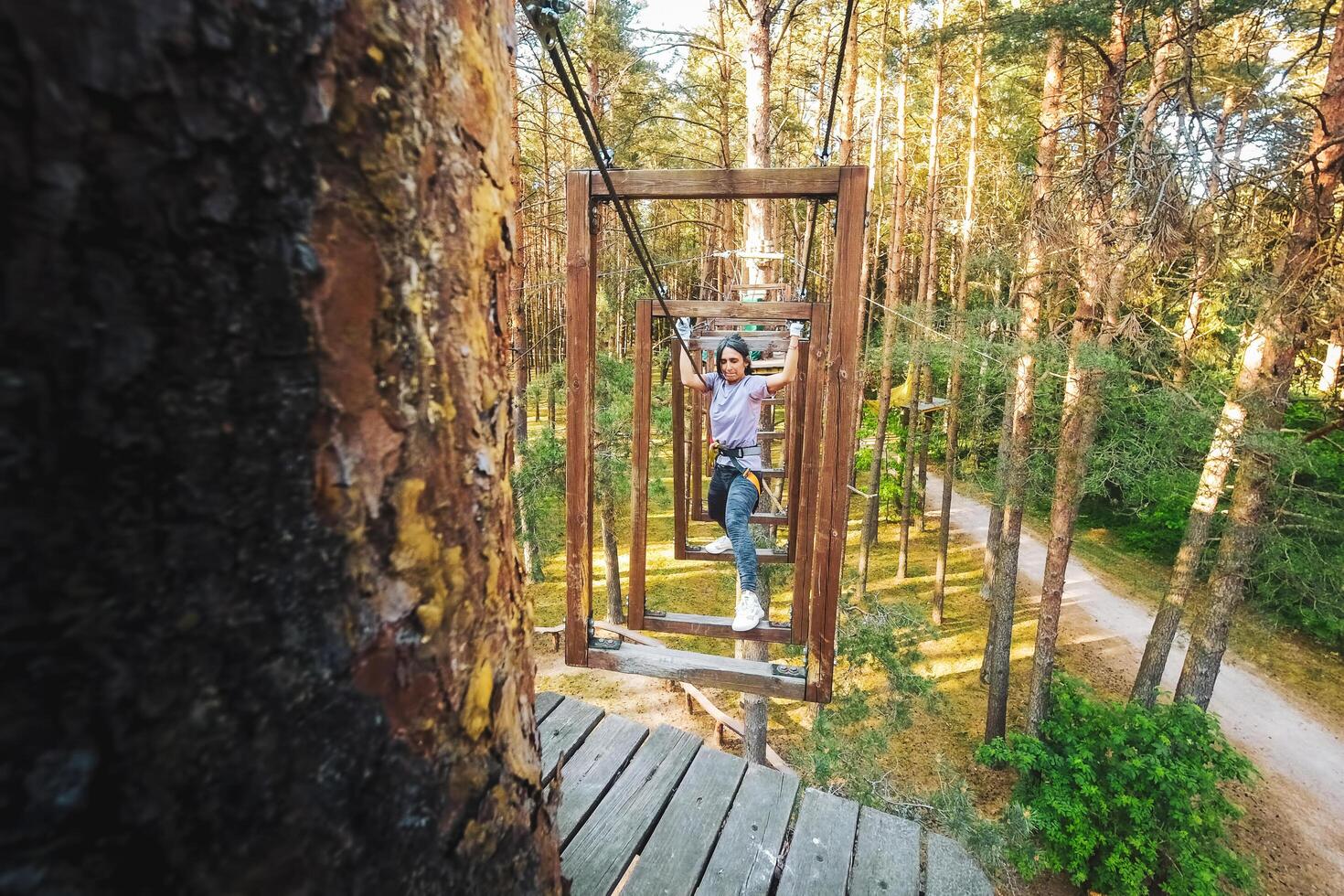 HBH,Palanga, Lithuania -2023 - woman solo in challenging obstacle tracks. Struggle passing physical climbing section. Strength and motivation. Active sports in adventure park photo