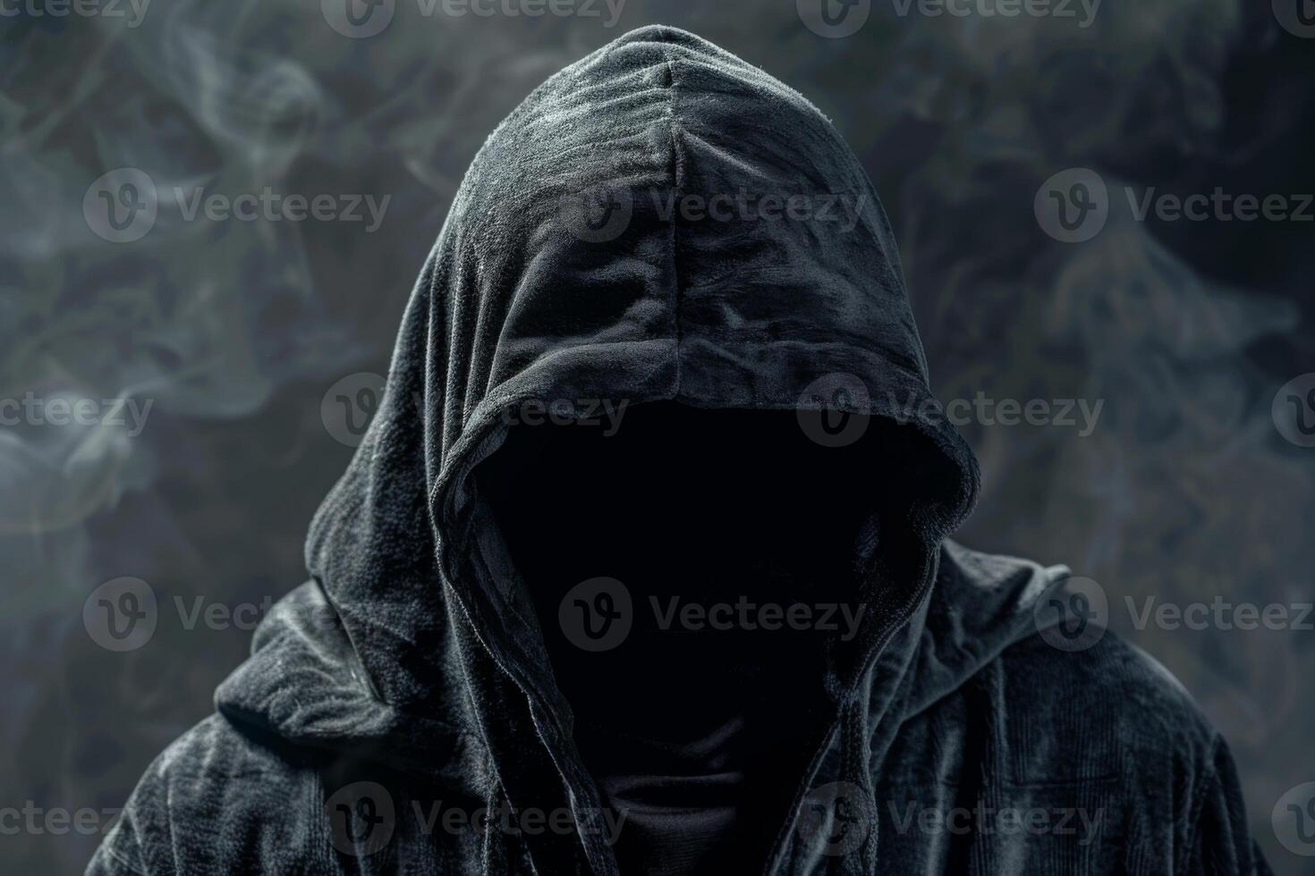 Man in a hood, a shadow hides his face on dark background. Anonymous crime concept photo