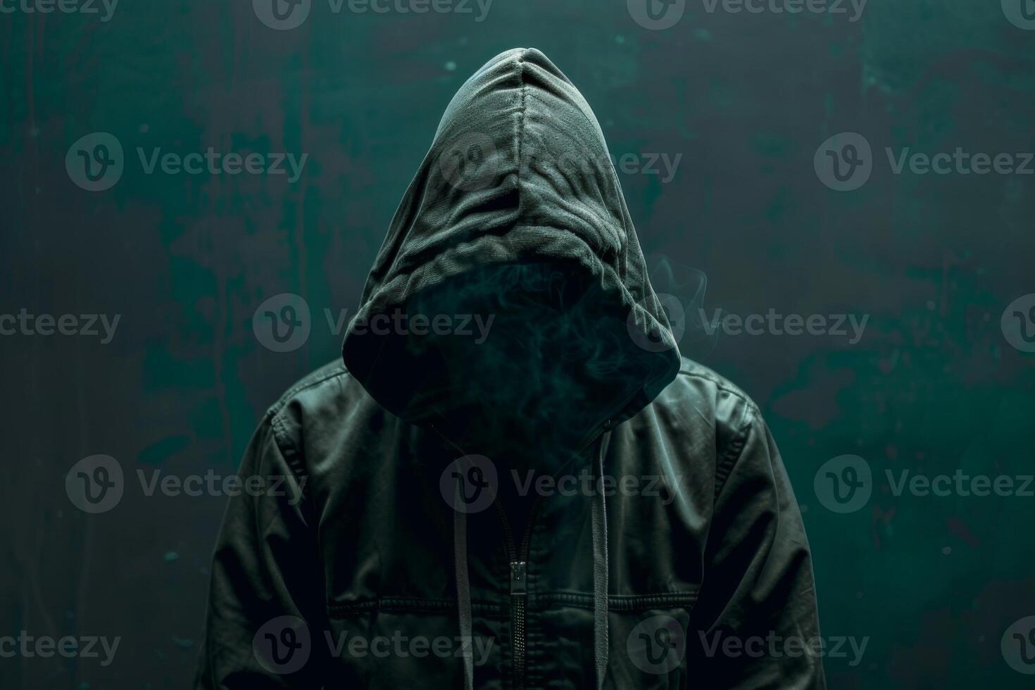 Man in a hood, a shadow hides his face on dark background. Anonymous crime concept photo