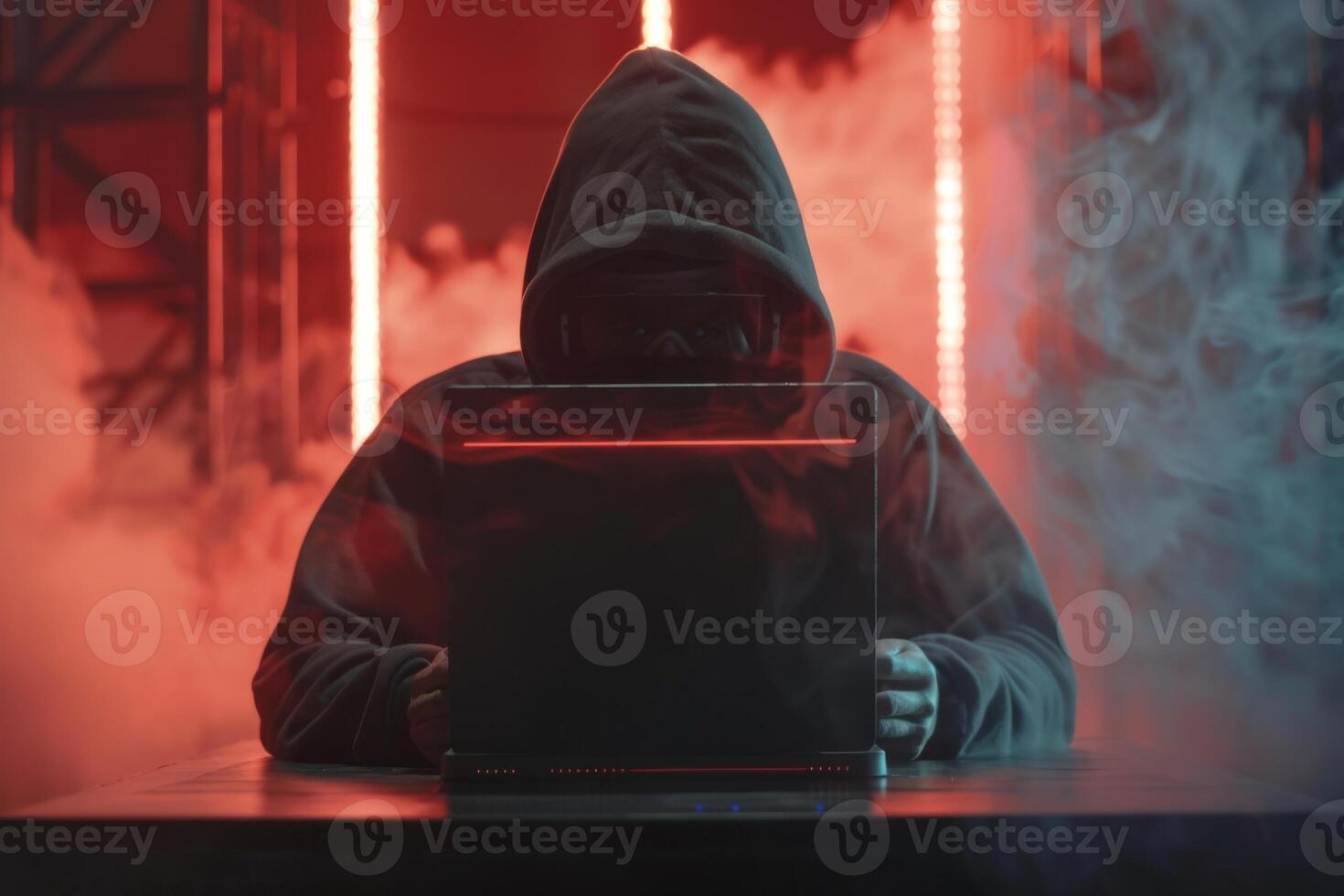 Hacker in hood hacking at computer in dark room. Computer criminal uses malware to hack devices photo