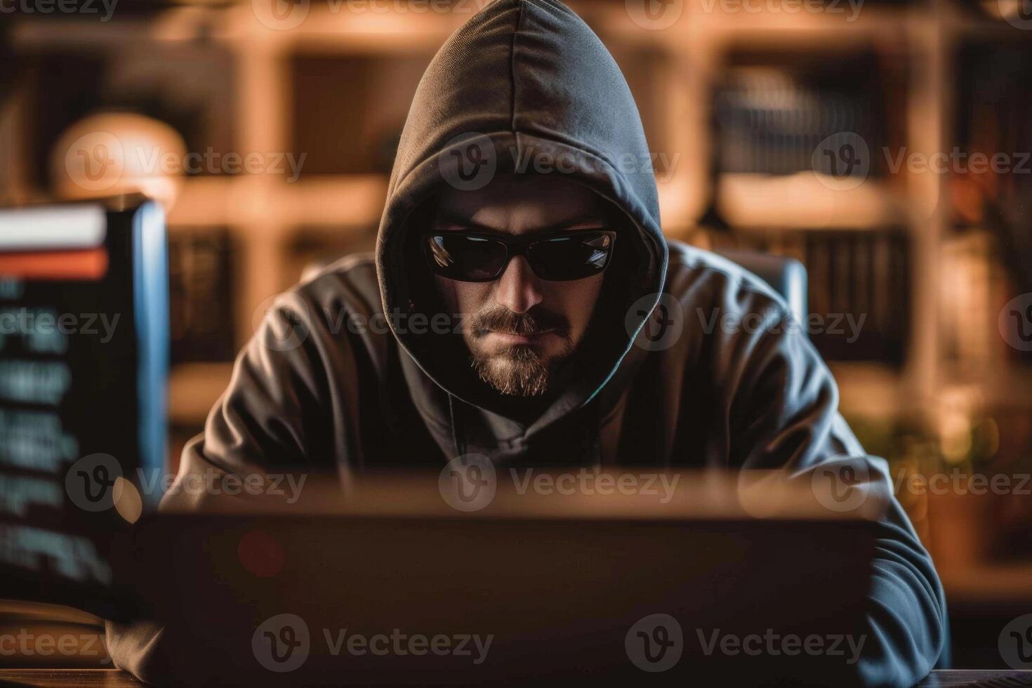 Hacker in hood hacking at computer in dark room. Computer criminal uses malware to hack devices photo