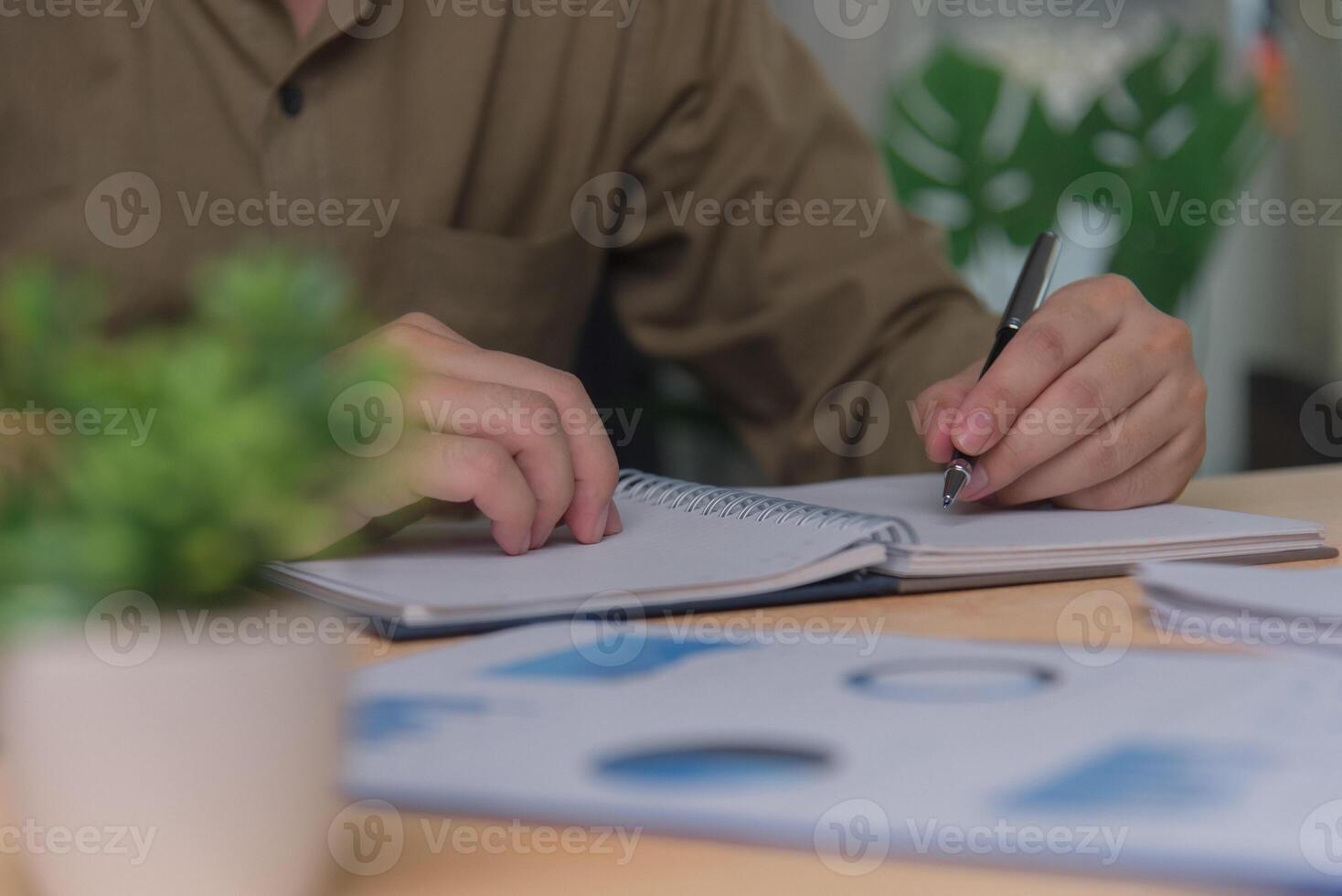 man hands with pen writing on notebook in the office.learning, education and work.writes goals, plans, make to do and wish list on desk. photo